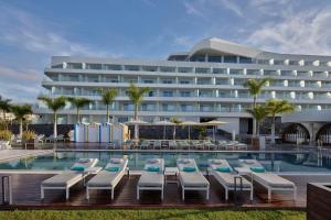 a hotel with a swimming pool and lounge chairs at Royal Hideaway Corales Beach - Adults Only in Adeje