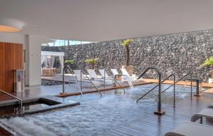 a swimming pool with white chairs and a stone wall at Royal Hideaway Corales Beach - Adults Only in Adeje