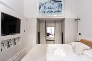 a bedroom with a white bed with a flat screen tv at The Bengal Tiger in Notting Hill in London
