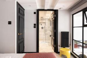 a bedroom with a black door and a yellow stool at The Bengal Tiger in Notting Hill in London