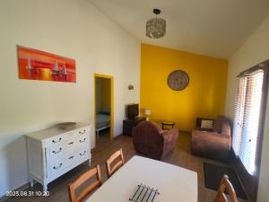 uma sala de estar com paredes amarelas e uma mesa e cadeiras em les gîtes du Mas ANNA em Céret