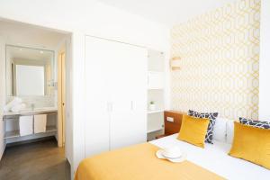 a bedroom with a bed with yellow pillows and a bathroom at Ona Living Barcelona in Hospitalet de Llobregat