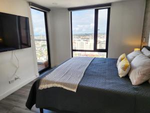 a bedroom with a large bed with large windows at Downtown Apartment with Balcony City View, Gym & Lounge in Tijuana