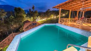 an outdoor swimming pool at night with a pergola at Zacs Valley Resort & Wellness Retreat Kodaikanal in Kodaikānāl