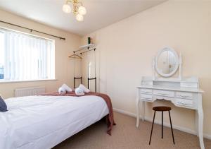 a bedroom with a bed and a dressing table and a mirror at Derby Mandarin 3 Bedroom Apartment with Garden and Parking in Derby