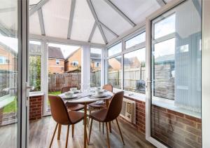 a dining room with a table and chairs and windows at Derby Mandarin 3 Bedroom Apartment with Garden and Parking in Derby