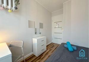 a small white bedroom with a bed and a chair at Sensational room 10 Min to Old Town Gdańsk,PKP & Shopping Mall in Gdańsk