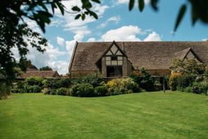 Bredon的住宿－Luxury Cottage with Swimming Pool，前面有绿色草坪的房子