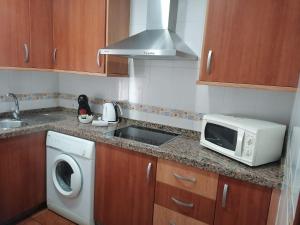a kitchen with a microwave and a washer and a sink at El Cano Playa Victoria Grupo AC Gestion in Cádiz