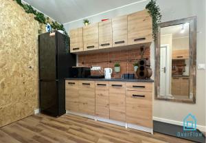 a kitchen with wooden cabinets and a black refrigerator at Sensational room 10 Min to Old Town Gdańsk,PKP & Shopping Mall in Gdańsk