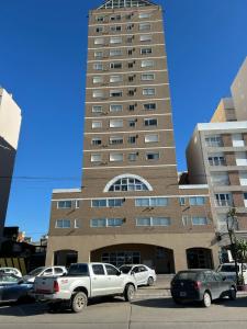 un edificio alto con coches estacionados frente a él en Marítima mono ambiente en Necochea