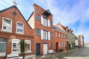 a red brick building with white windows on a street at Altes Kontorhaus Backbord in Husum