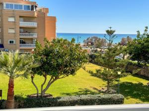 Blick auf einen Park mit Palmen und ein Gebäude in der Unterkunft Apartamento con vistas al mar a 1 min de la playa in Málaga