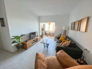 ein Wohnzimmer mit einem Sofa und einem TV in der Unterkunft Apartamento con vistas al mar a 1 min de la playa in Málaga