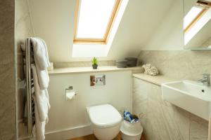 a bathroom with a toilet and a sink and a window at La Pulente Cottages in St. Brelade +36 photos