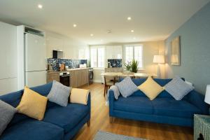 a living room with a blue couch and a kitchen at La Pulente Cottages in St. Brelade