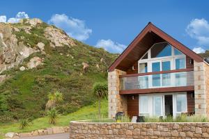 a house with a mountain in the background at La Pulente Cottages in St. Brelade