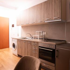 een keuken met houten kasten, een spoelbak en een vaatwasser bij Suprem Apartment Modern Studio Near City Center, Self Check-in & Fast Wi-Fi in Tirana