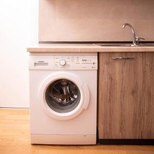 een wasmachine in een keuken met een wastafel bij Suprem Apartment Modern Studio Near City Center, Self Check-in & Fast Wi-Fi in Tirana