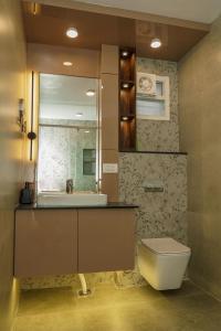ein Badezimmer mit einem Waschbecken, einem WC und einem Spiegel in der Unterkunft Williams Park Suite in Bangalore