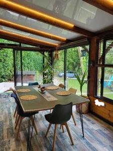 een eetkamer met een tafel, stoelen en ramen bij Maison de vacances: chez Nirina in Mortagne-sur-Sèvre