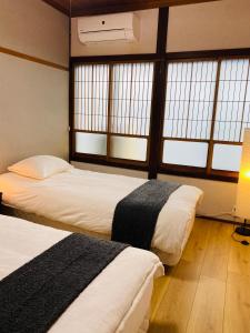 2 camas en una habitación con 2 ventanas en Karin House, en Takayama