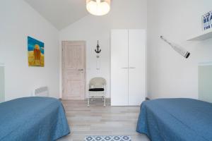 um quarto branco com 2 camas e uma cadeira em Strandpark Sierksdorf H026 em Sierksdorf