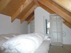 ヴェスターラントにあるHaus-Hookipa-App-2の木製天井の客室の白いベッド1台分です。