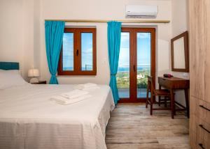 a bedroom with a bed with blue curtains and a desk at Maroulas Natura Palace in Giannoudi