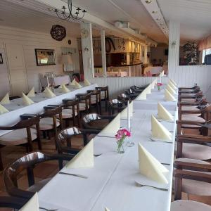 a long row of tables and chairs with flowers on them at Maalaiskartano Pihkala in Kestilä