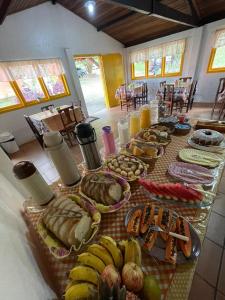 una mesa larga con plátanos y otros alimentos. en Pousada Bela Vista en Penedo