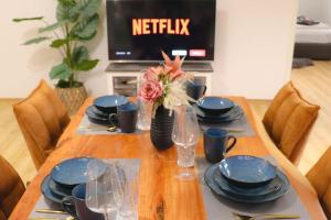 a wooden table with blue plates and glasses and a television at EcoCube 442 - Balkon, 2Zimmer, Waschmaschine, Schlafsofa in Meppen +16 photos