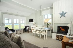 a living room with a table and a fireplace at Point Cottages, Bamburgh in Bamburgh