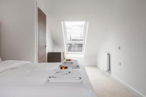 um quarto branco com toalhas numa cama em Beautiful New Semi-detached 3 BR House wGarden em Brentford