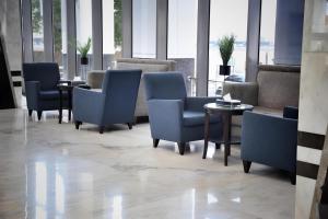 a waiting room with chairs and tables and windows at Zaha Taiba Hotel in Al Madinah