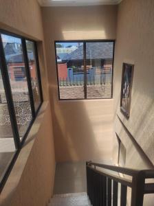 a staircase with three windows in a building with a stair case at Brand new crane Apartments in Lenasia