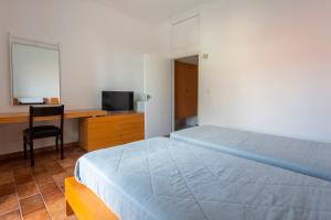 a bedroom with a bed and a desk and a television at Hotel Roumani in Spetses