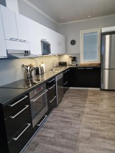 uma cozinha com electrodomésticos pretos e armários brancos em Villa Sara em Kalajoki