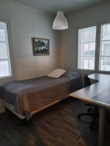 a bedroom with a bed and a desk and windows at Villa Sara in Kalajoki