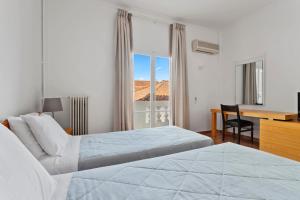 a hotel room with two beds and a desk and a window at Hotel Roumani in Spetses