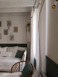 Maison Charmeilles - Gîte touristique - Coliving في Fronsac: غرفة نوم بسرير وكرسي بجانب نافذة