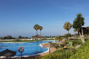a large swimming pool with umbrellas and palm trees at Lunamar El mejor Resort en la mejor Playa in Marbella