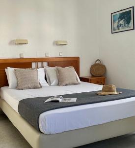 a bed with a hat and a book on it at Ammosis Inn in Naxos Chora