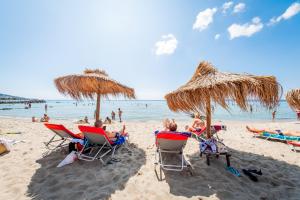 people sitting in chairs on a beach with umbrellas at Prestige Fort Beach - Full Board in Sveti Vlas