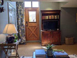 a living room with a television and a wooden door at Luxury Cottage with Swimming Pool in Bredon