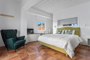 a bedroom with a large bed and a green chair at Hotel Roumani in Spetses