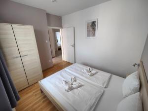 a white bedroom with two white towels on a bed at Corvin Plaza Apartments & Suites in Budapest