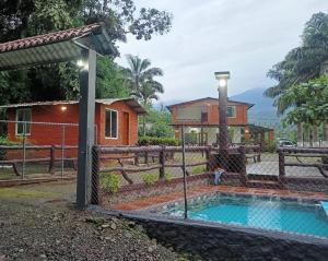 a house with a swimming pool in front of a fence at Las Orquideas ( Rural house ) in Cumanda