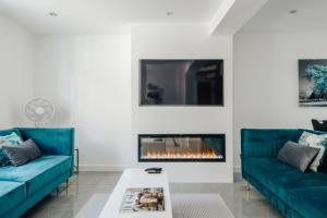 a living room with two blue couches and a fireplace at Exceptional Whole House Chelsea with Roof Terrace in London