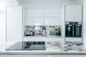 a white kitchen with marble counter tops and appliances at Exceptional Whole House Chelsea with Roof Terrace in London